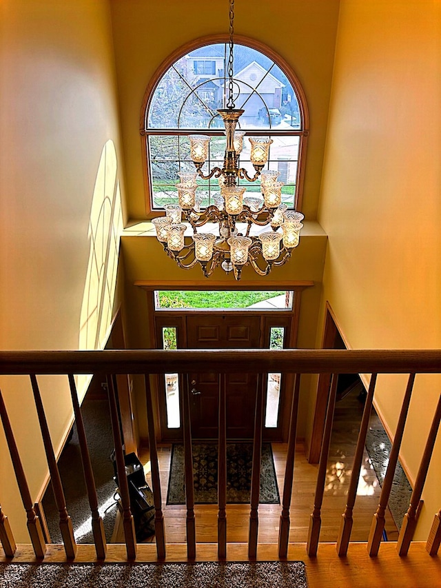 stairway featuring wood-type flooring and a notable chandelier