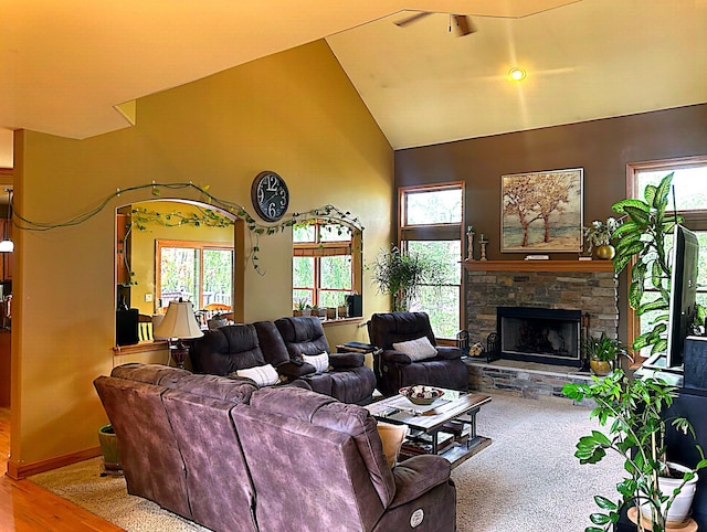 living room with a stone fireplace, high vaulted ceiling, hardwood / wood-style floors, and a healthy amount of sunlight