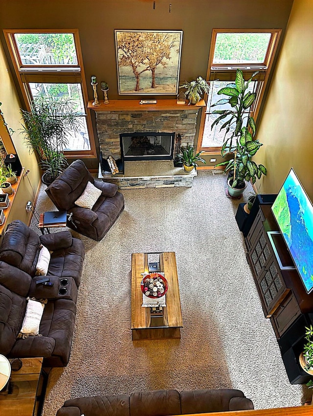 carpeted living room with a stone fireplace and a healthy amount of sunlight