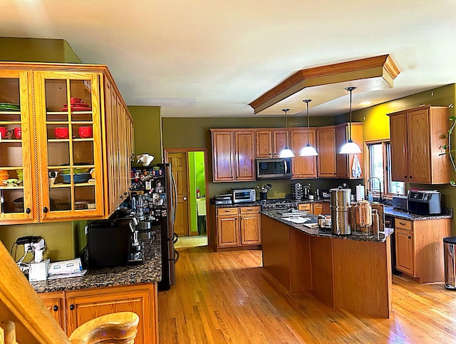 kitchen featuring pendant lighting, stainless steel appliances, a center island, and light hardwood / wood-style flooring