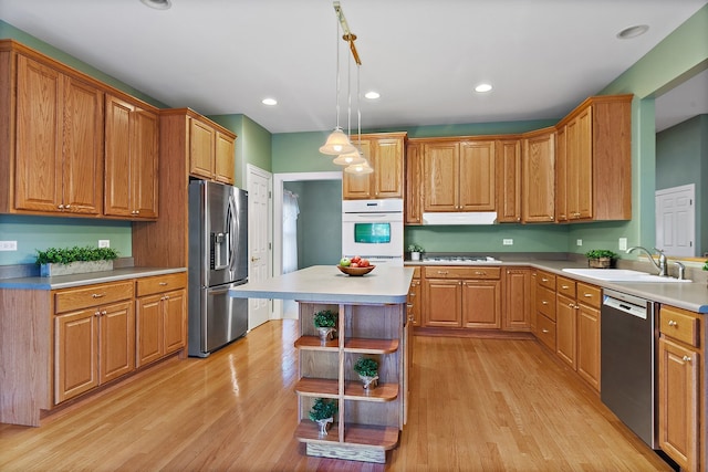 kitchen with a center island, sink, hanging light fixtures, light hardwood / wood-style flooring, and appliances with stainless steel finishes