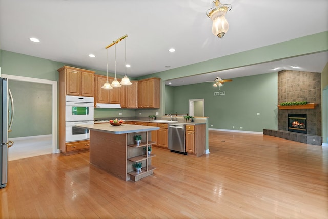 kitchen with light hardwood / wood-style flooring, stainless steel appliances, hanging light fixtures, and a center island