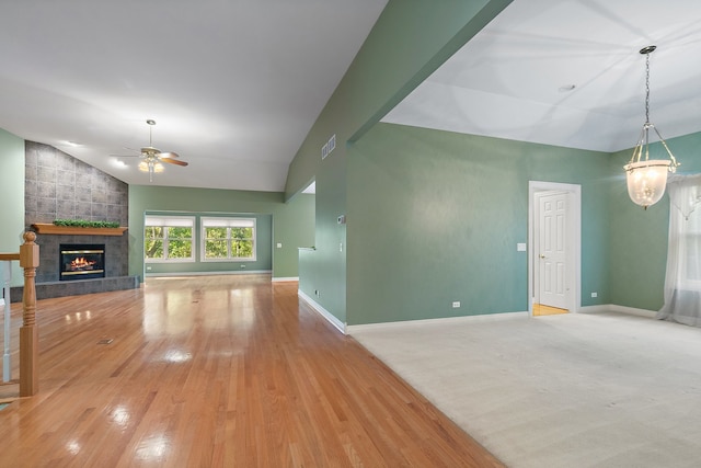 unfurnished living room featuring ceiling fan, lofted ceiling, a fireplace, and light hardwood / wood-style flooring