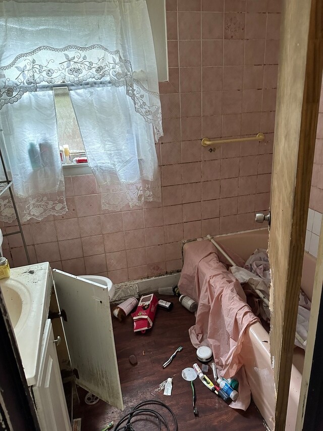 bathroom with shower / bathtub combination, tile walls, hardwood / wood-style flooring, and vanity