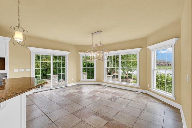 unfurnished dining area featuring baseboards, visible vents, a chandelier, and a healthy amount of sunlight