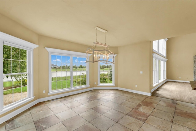 unfurnished dining area featuring baseboards, visible vents, an inviting chandelier, and plenty of natural light