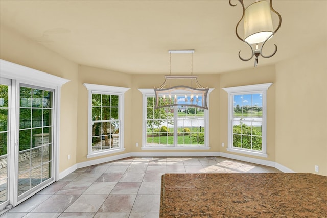 unfurnished dining area featuring light tile patterned floors and a chandelier