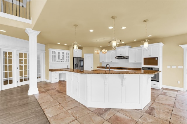 kitchen featuring a large island with sink, white cabinetry, stainless steel appliances, and pendant lighting