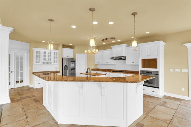 kitchen with stainless steel appliances, under cabinet range hood, light tile patterned flooring, a large island with sink, and recessed lighting