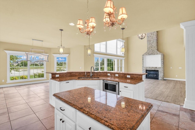 kitchen featuring an inviting chandelier, a center island with sink, dark stone countertops, and a sink