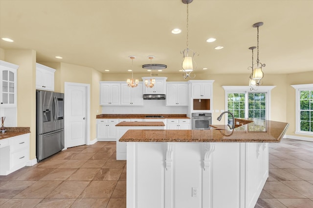 kitchen with decorative light fixtures, white cabinets, appliances with stainless steel finishes, and dark stone counters