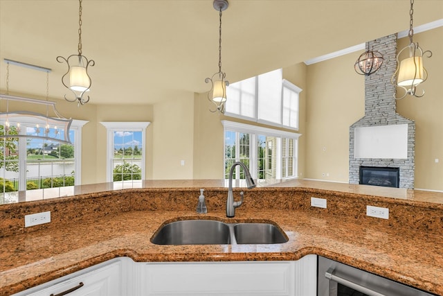 kitchen with pendant lighting, a fireplace, crown molding, and sink