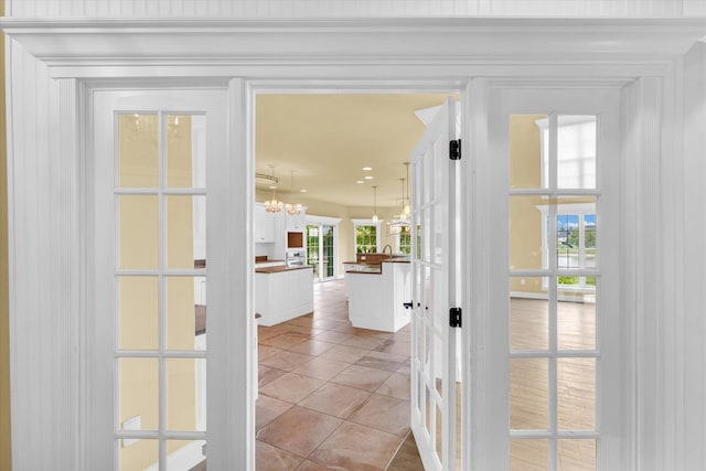 hall with a healthy amount of sunlight, light tile patterned floors, and a chandelier