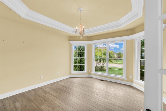 unfurnished room featuring wood-type flooring, a raised ceiling, a notable chandelier, and ornamental molding