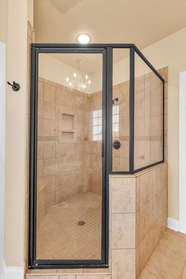 full bathroom featuring a stall shower, tile patterned flooring, a chandelier, and baseboards