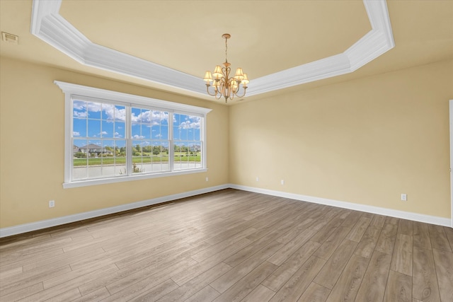 unfurnished room with a raised ceiling, a chandelier, and light hardwood / wood-style floors