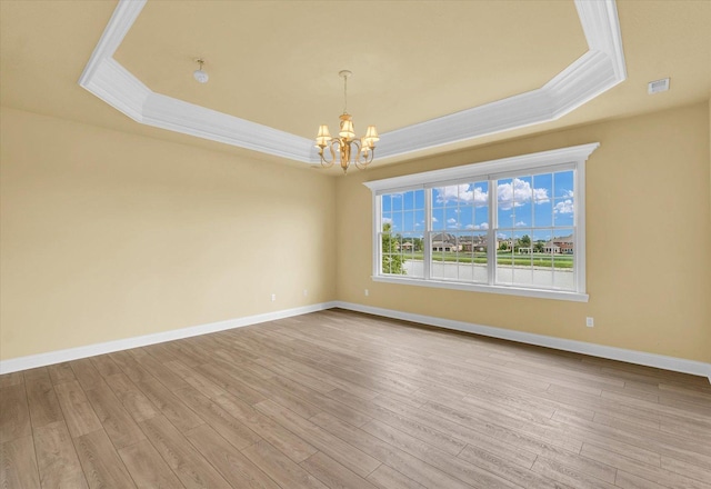 empty room with ornamental molding, a chandelier, and a tray ceiling