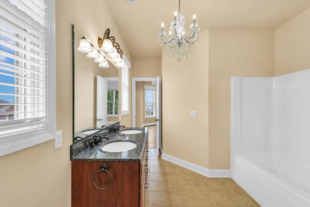 full bath with tile patterned floors, a bathing tub, a notable chandelier, and a sink