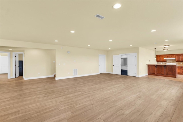unfurnished living room featuring visible vents, light wood-style flooring, and baseboards