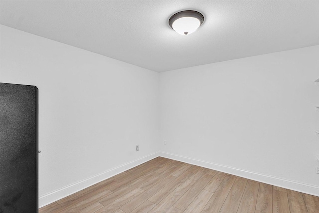 empty room with baseboards and light wood-style flooring