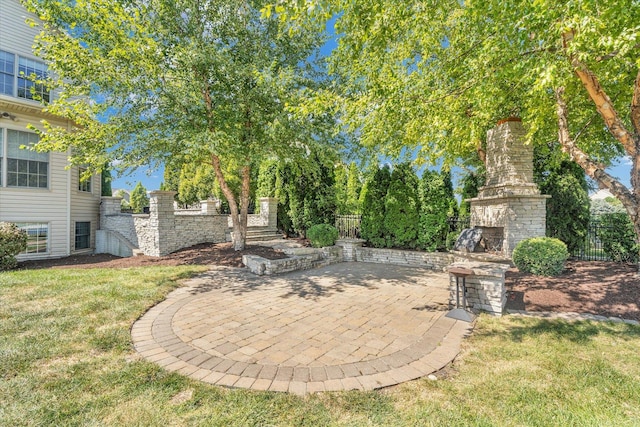 view of yard with a patio, fence, and an outdoor stone fireplace