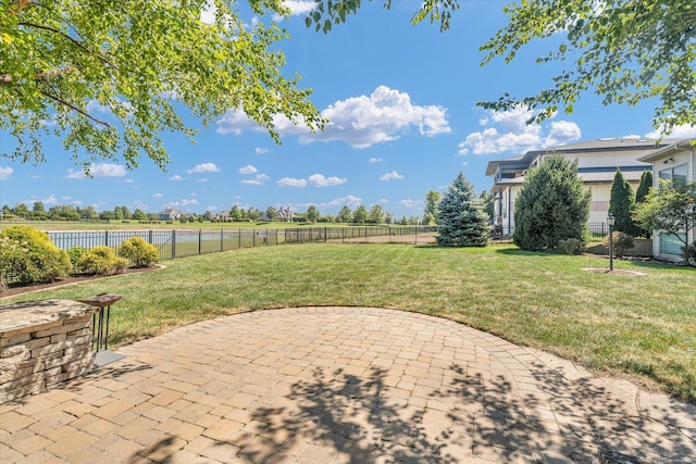 view of yard with a patio, a fenced backyard, and a water view