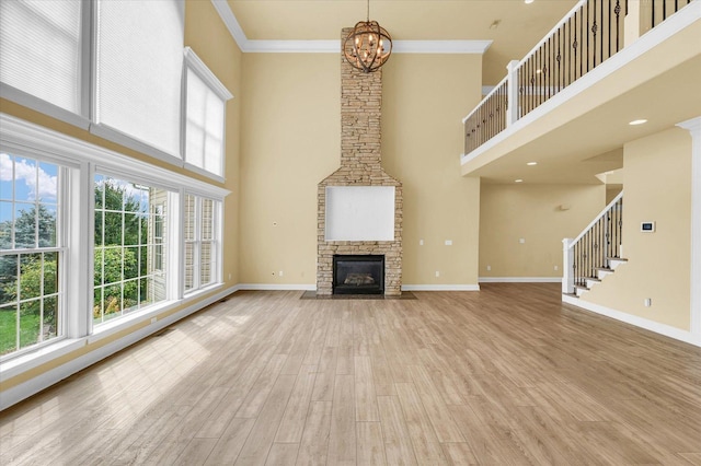 unfurnished living room featuring baseboards, a chandelier, a wealth of natural light, and a towering ceiling