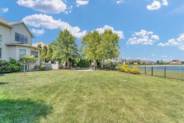 view of yard featuring a residential view, a water view, and fence