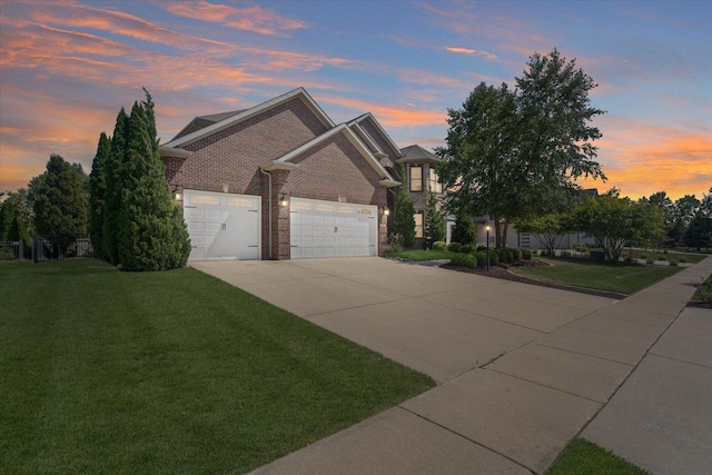 view of front of property featuring a lawn, driveway, an attached garage, and brick siding