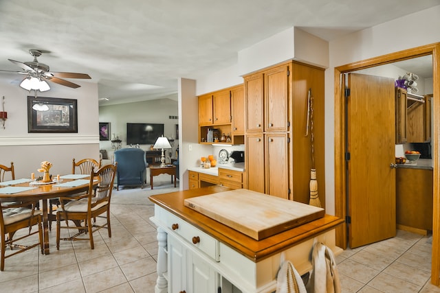 kitchen featuring ceiling fan, vaulted ceiling, white cabinets, and light tile patterned flooring