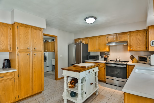 kitchen with washer / clothes dryer, sink, light tile patterned floors, and appliances with stainless steel finishes