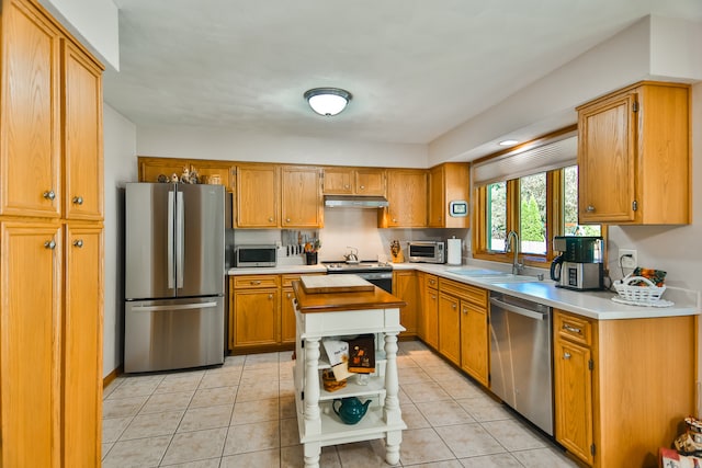 kitchen featuring a kitchen island, sink, light tile patterned floors, and appliances with stainless steel finishes