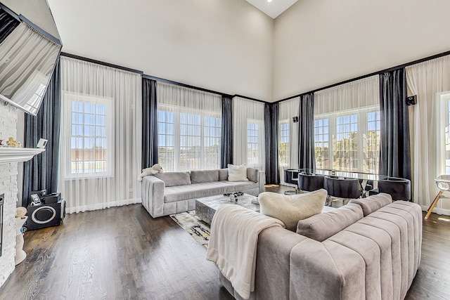 living room featuring a fireplace, dark hardwood / wood-style flooring, a healthy amount of sunlight, and a towering ceiling