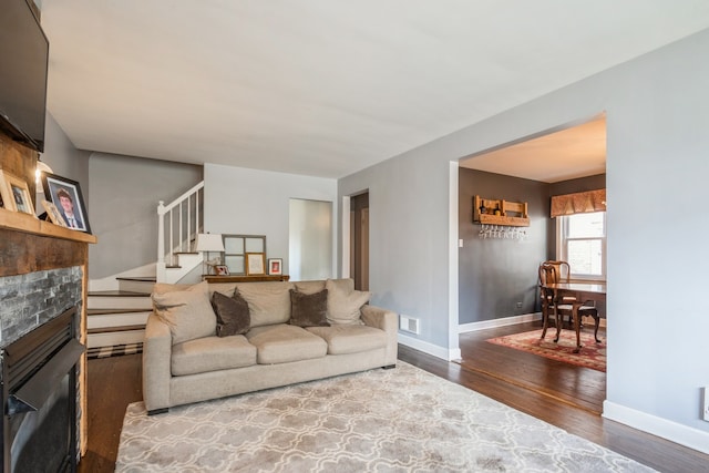 living room featuring a stone fireplace and hardwood / wood-style flooring