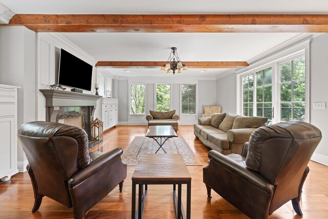 living room with crown molding, plenty of natural light, light hardwood / wood-style flooring, and a notable chandelier