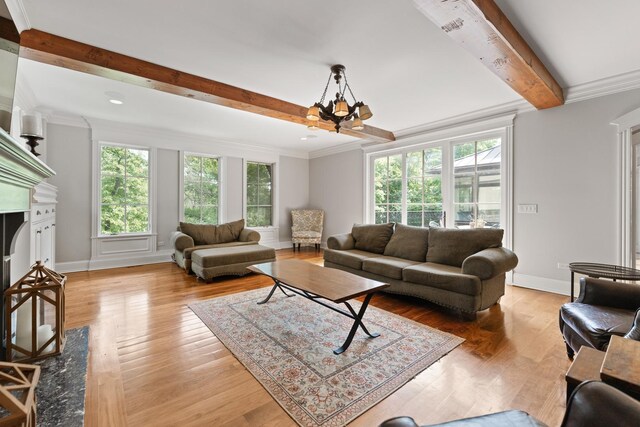 living room featuring a chandelier, light hardwood / wood-style floors, beamed ceiling, and ornamental molding