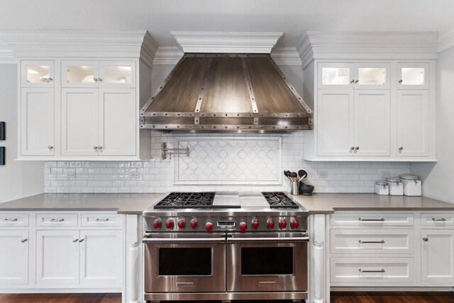 kitchen with custom range hood, double oven range, white cabinets, and decorative backsplash