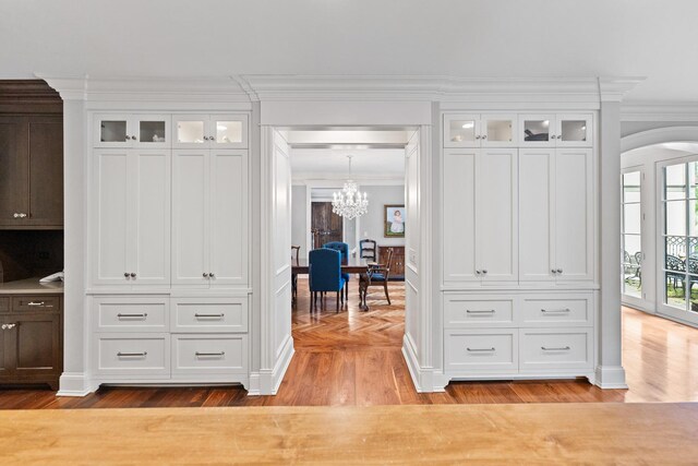 corridor with light hardwood / wood-style floors, a chandelier, and ornamental molding