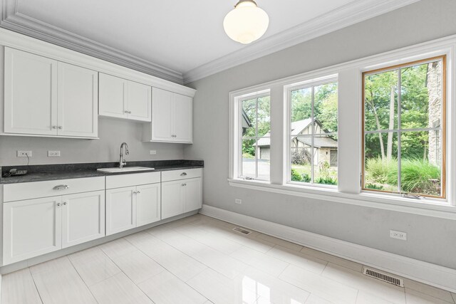 kitchen featuring ornamental molding, light tile patterned floors, white cabinetry, and sink