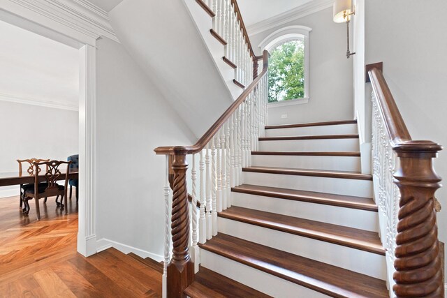 stairs featuring parquet flooring and crown molding