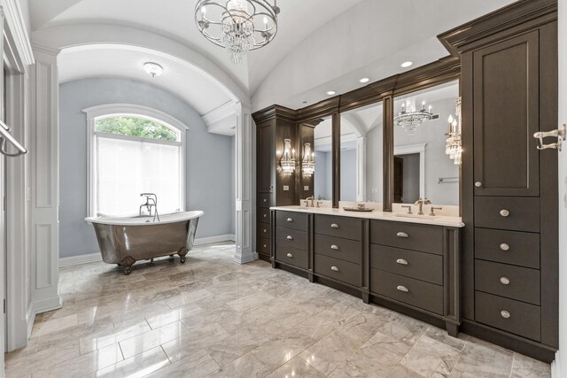 bathroom with vaulted ceiling, a washtub, an inviting chandelier, and vanity