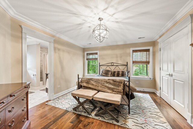 bedroom featuring multiple windows, wood-type flooring, ensuite bathroom, and ornamental molding