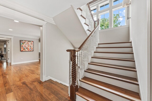 staircase featuring ornamental molding and hardwood / wood-style flooring