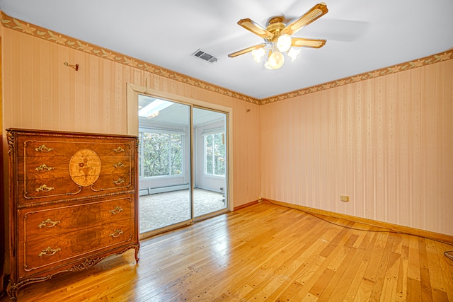 spare room featuring baseboard heating, ceiling fan, and light hardwood / wood-style floors