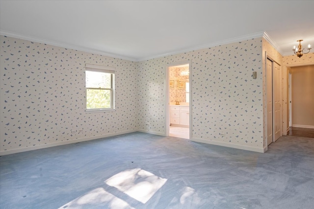 carpeted empty room featuring a notable chandelier and crown molding