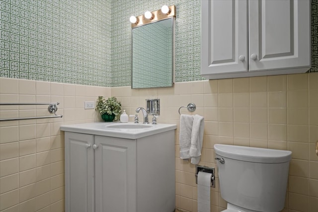 bathroom featuring vanity, tile walls, and toilet