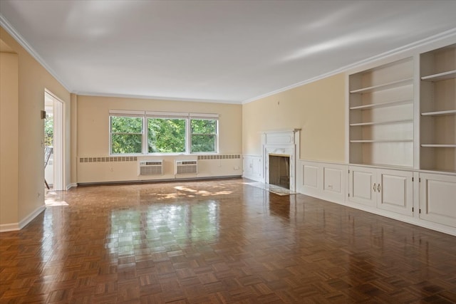 unfurnished living room with built in features, ornamental molding, dark parquet flooring, a fireplace, and an AC wall unit