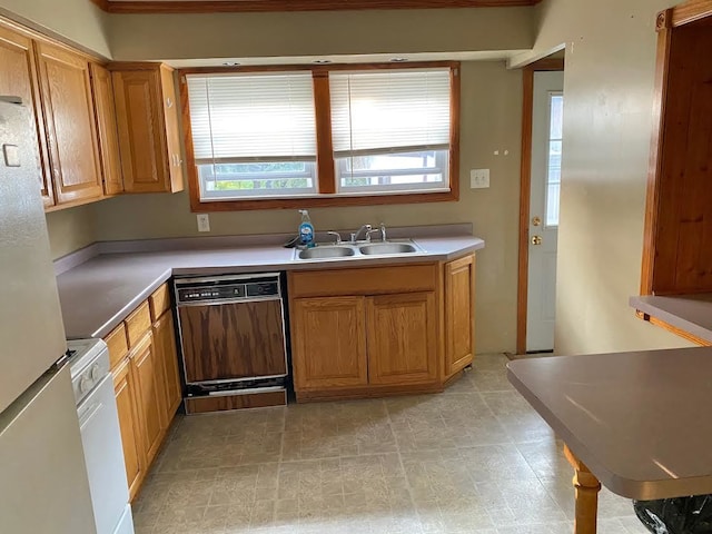 kitchen with crown molding, black dishwasher, stainless steel refrigerator, and sink