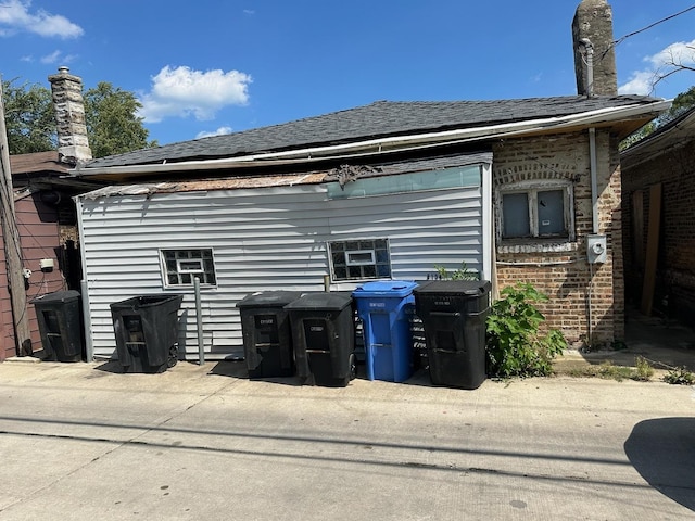 view of property exterior with brick siding and roof with shingles