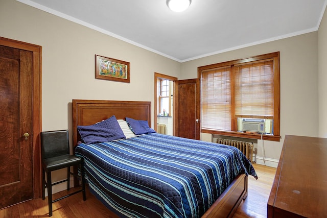 bedroom featuring radiator, crown molding, baseboards, cooling unit, and wood finished floors